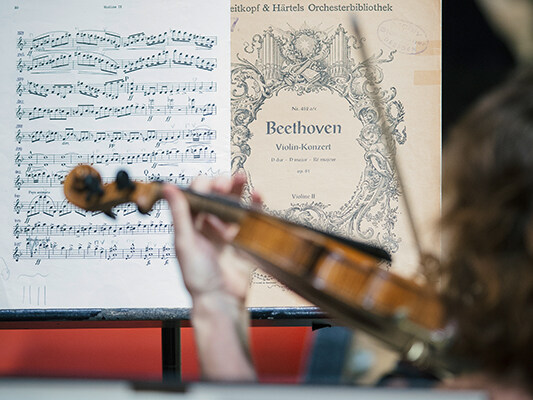 Detailaufnahme einer Violinistin mit Beethoven-Noten © Semperoper Dresden/Oliver Killig Blick über die Schulter einer Violinistin mit Notenmaterial von Beethoven auf dem Pult