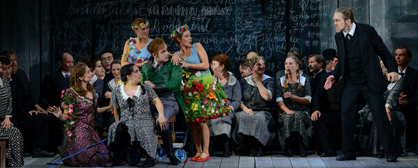 Szene aus "Der Wildschütz": Recht und links sind zwei Sänger, der rechts Sitzende ist umringt von 4 Sängerinnen