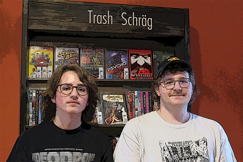 Emil Huck und Robin Goldbach von der Filmgalerie Phase IV e.V. vor dem Regal für Trash & Schräges